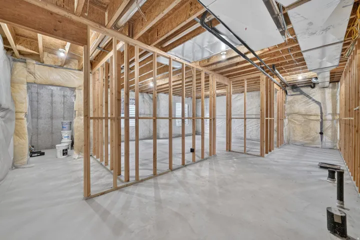 Framed interior with exposed wooden ceiling joists, concrete flooring, and insulated walls