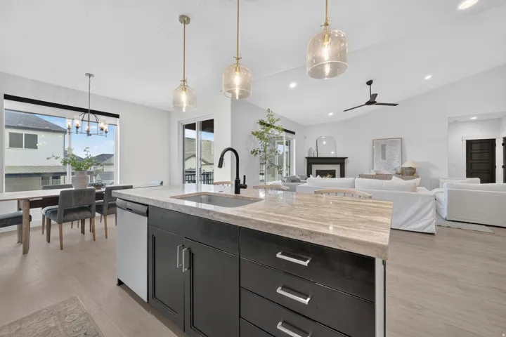 Kitchen island with an undermount sink, dark cabinetry, and light-toned countertop