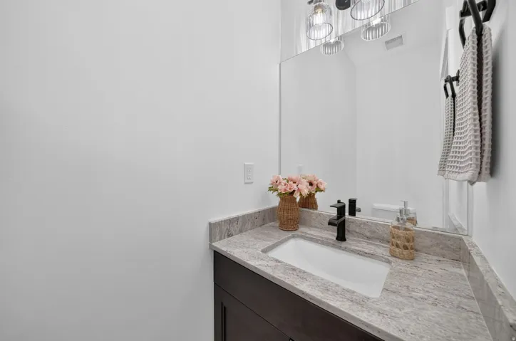 Vanity with a white rectangular sink, dark wood-finish cabinetry, and a light-toned countertop
