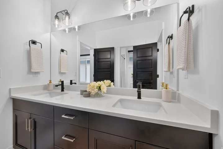 Dual sink vanity with dark wood-finish cabinetry and white countertops