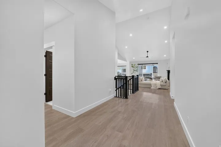 Vaulted ceilings, recessed lighting, wood-finish flooring, and a black open-spindle railing