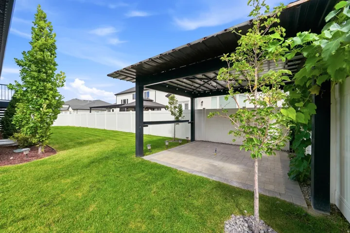 Expansive backyard featuring a covered patio with string lighting, paver patio, a manicured lawn, and privacy fencing