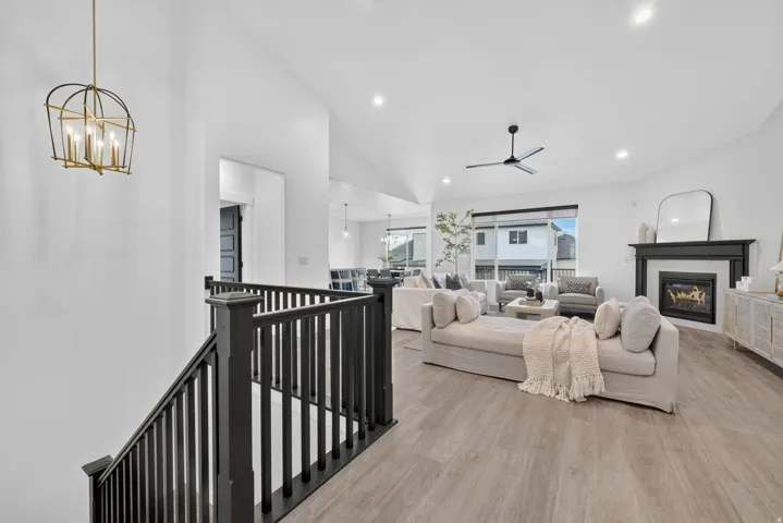 Spacious living area featuring wood-finish flooring, a fireplace with dark mantel, and recessed lighting