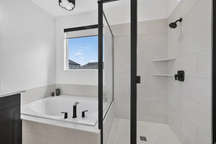 Built-in soaking tub with matte black fixtures, separate shower with glass enclosure, white subway tile shower surround, and a hexagonal tile shower floor