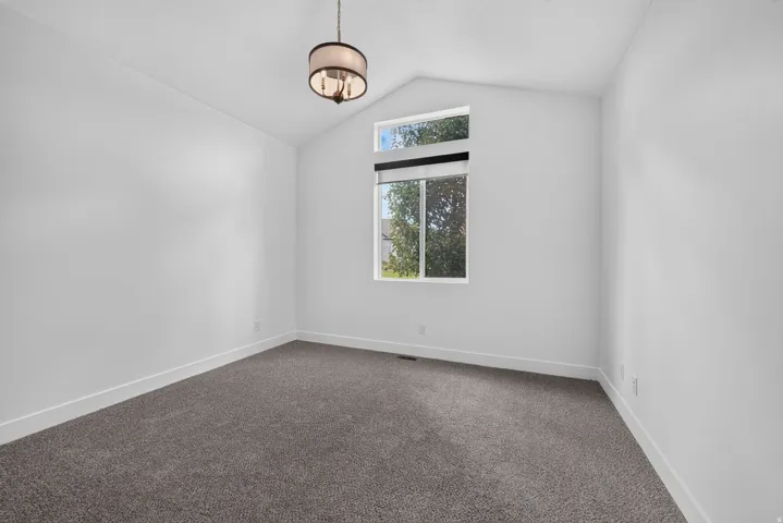 Vaulted ceiling, contemporary drum pendant light, large window with transom, neutral carpet, white walls