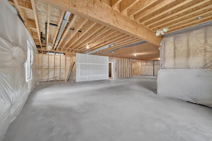 Unfinished basement with concrete flooring, exposed wood joists, and framed interior walls