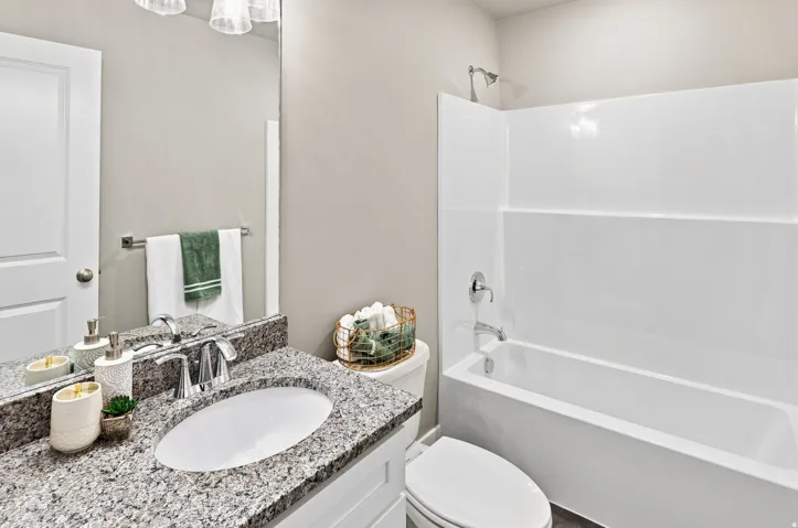 Vanity with granite-style countertop, undermount sink, chrome faucet, and overhead light fixture