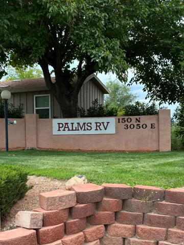 Entryway signage with a textured stucco finish and integrated address numbers, surrounded by a manicured lawn and mature landscaping