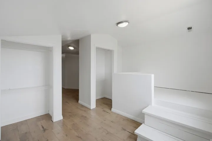 Wood-finish flooring, recessed lighting, white painted walls, built-in shelving, and a short staircase