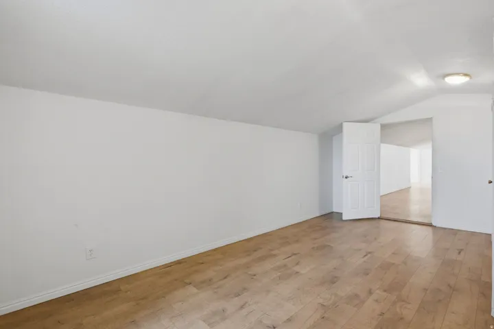 Wood-finish flooring with white walls and a white interior door
