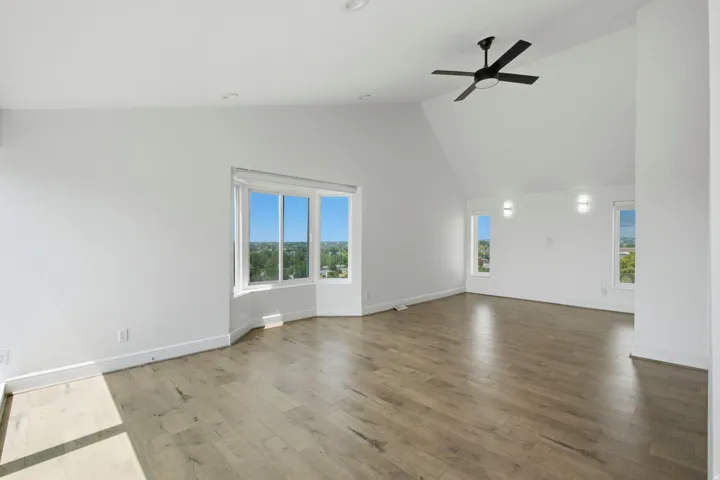 Vaulted ceiling with a contemporary ceiling fan, wood-finish flooring, recessed lighting, and a bay window