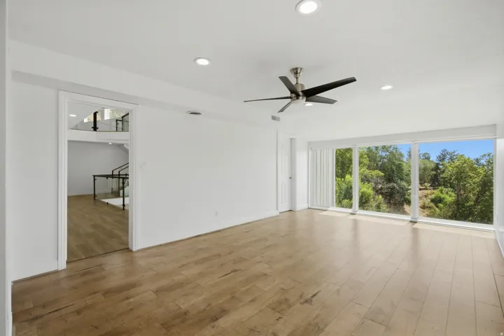Spacious room featuring wood-finish flooring, recessed lighting, and a ceiling fan