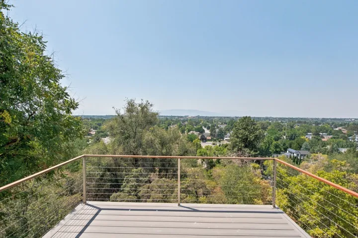 Deck featuring composite decking, cable railing with wood-finish top rail, and extensive tree canopy