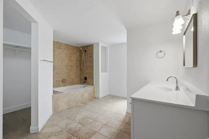 White vanity with integrated sink, chrome faucet, and rectangular mirror