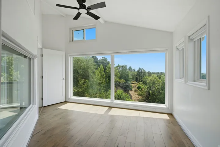 Vaulted ceilings, wood-finish flooring, full-light door, and expansive windows