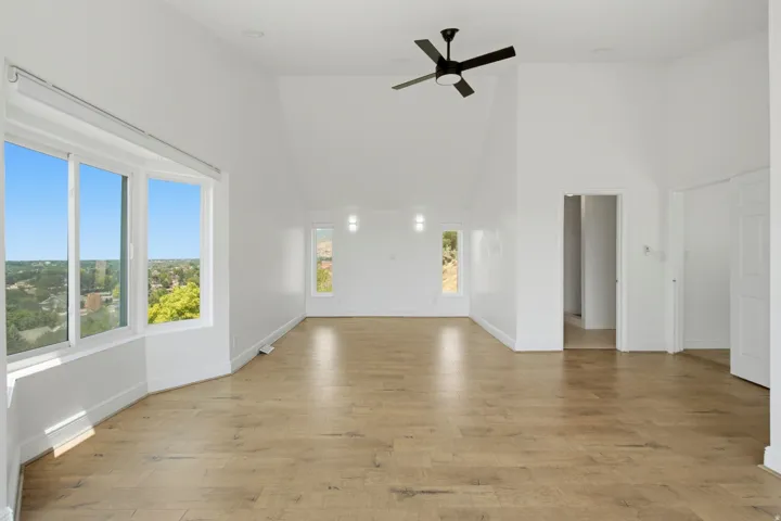 Vaulted ceilings, wood-finish flooring, and a contemporary ceiling fan