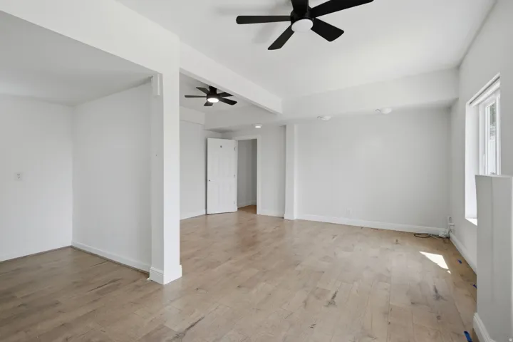 Spacious interior with wood-finish flooring, white walls, and multiple ceiling fans