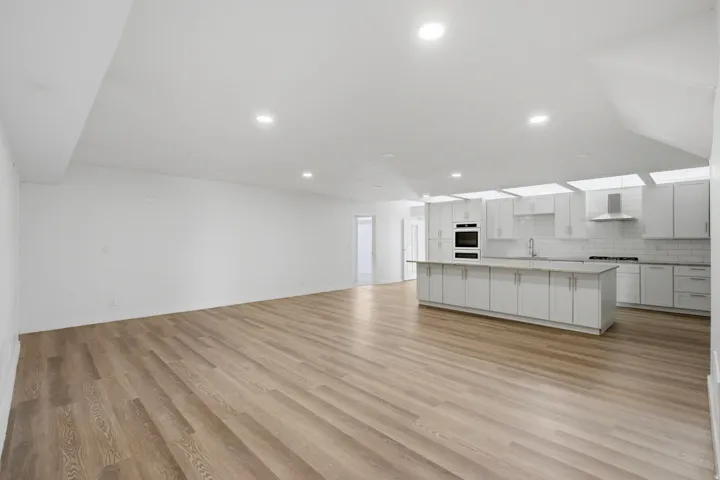Open concept living space featuring wood-finish flooring, recessed lighting, and a modern kitchen