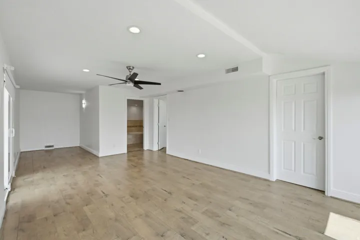 Wood-finish flooring with recessed lighting, ceiling fan, and sliding glass door