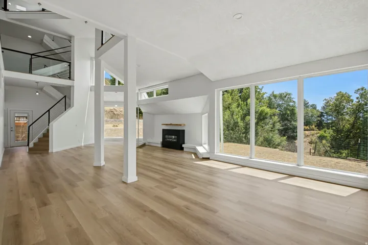 Vaulted ceilings, wood-finish flooring, a contemporary fireplace, and floor-to-ceiling windows