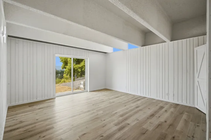 Wood-finish flooring with white vertical paneling and exposed ceiling beams