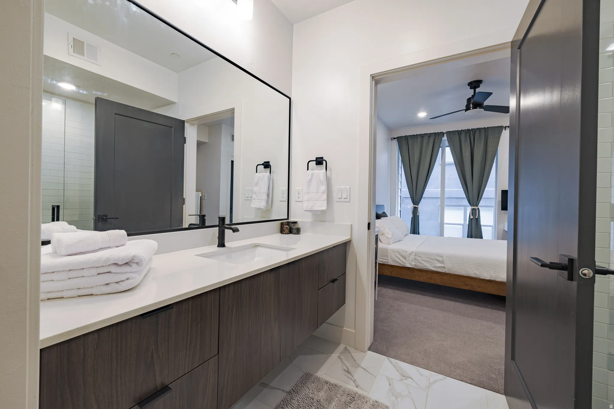 Primary Bathroom: Floating vanity with a light-toned countertop and matte black fixtures