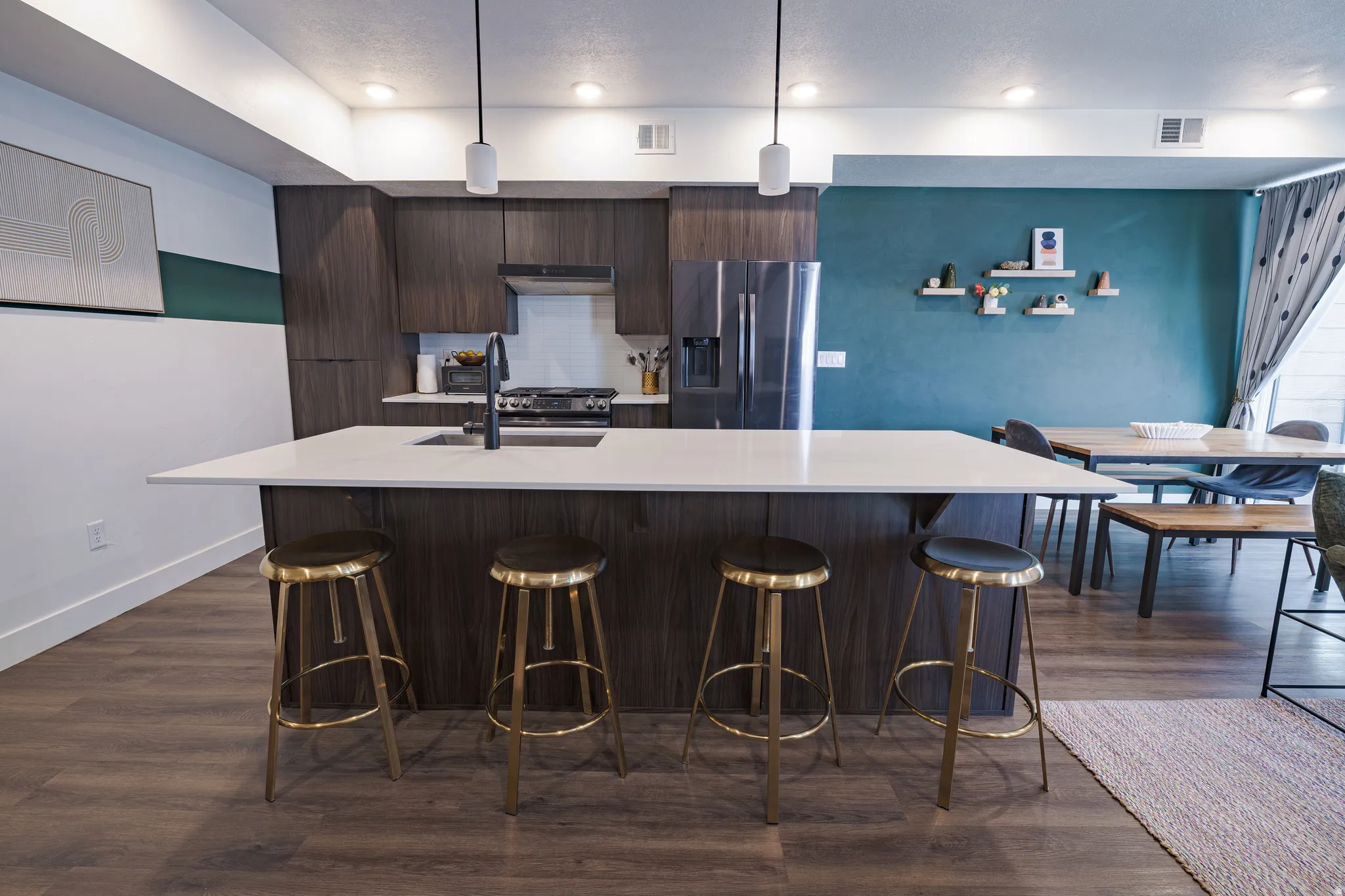 Contemporary kitchen featuring dark wood-finish cabinetry, a large center island with a light-toned countertop, and modern pendant lighting