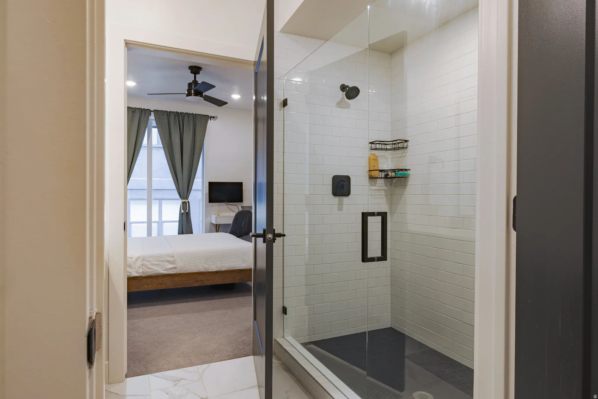 Primary Bathroom: Glass-enclosed shower with subway tile surround, dark shower pan, and matte black fixtures