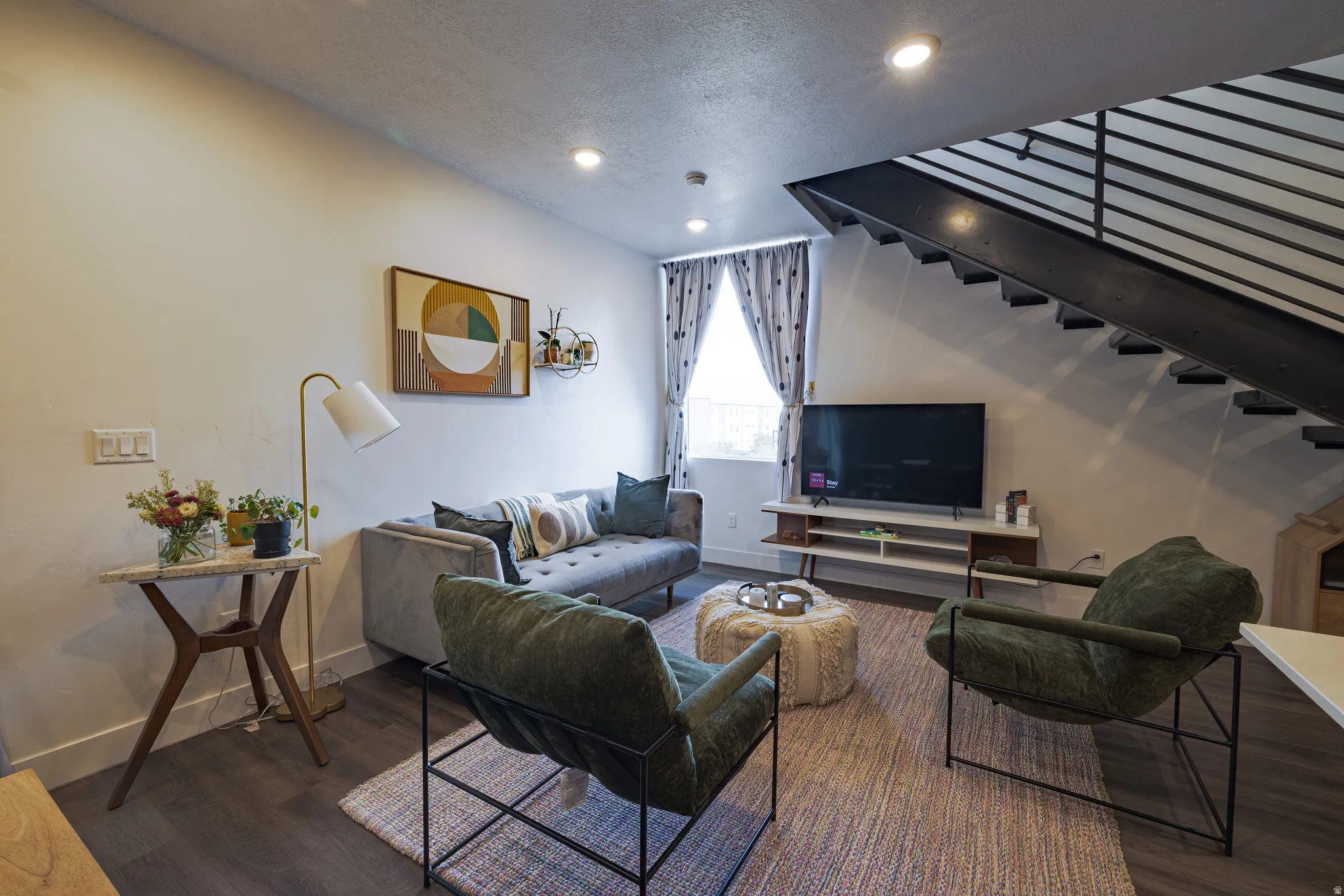 Dark wood-finish flooring, recessed lighting, and an open-tread staircase with metal railing