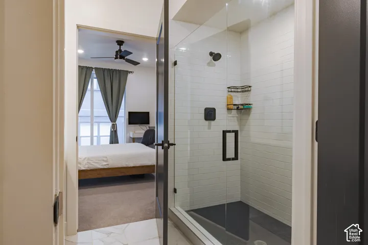 Primary Bathroom: Glass-enclosed shower with subway tile surround, dark shower pan, and matte black fixtures