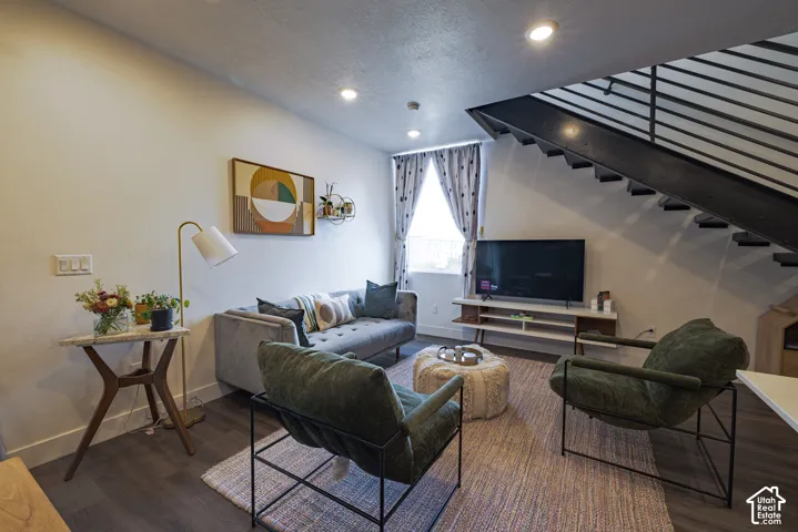 Dark wood-finish flooring, recessed lighting, and an open-tread staircase with metal railing