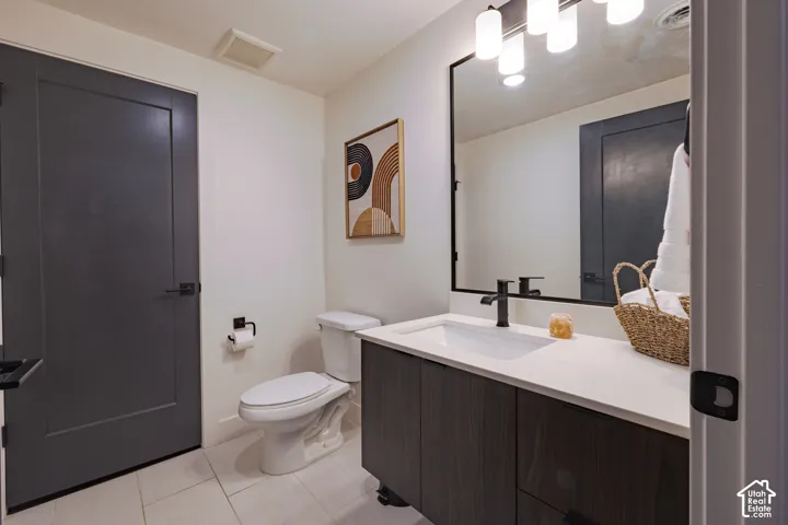 Powder Bathroom: Modern vanity with white countertop and integrated sink, matte black faucet, dark wood-finish cabinetry, rectangular framed mirror, and white tile flooring