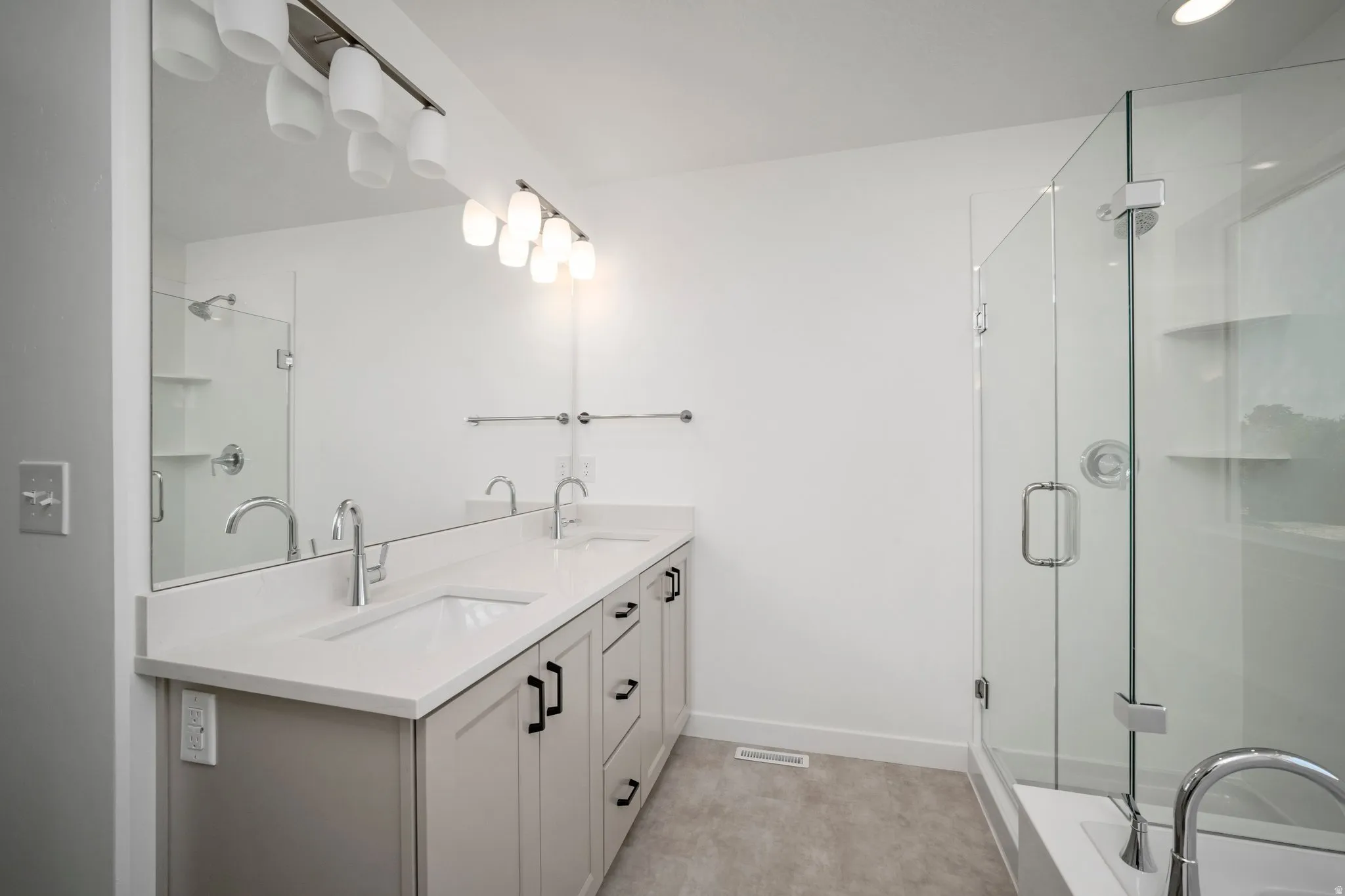 Dual vanity with undermount sinks, stone-finish countertops, and matte black cabinet hardware