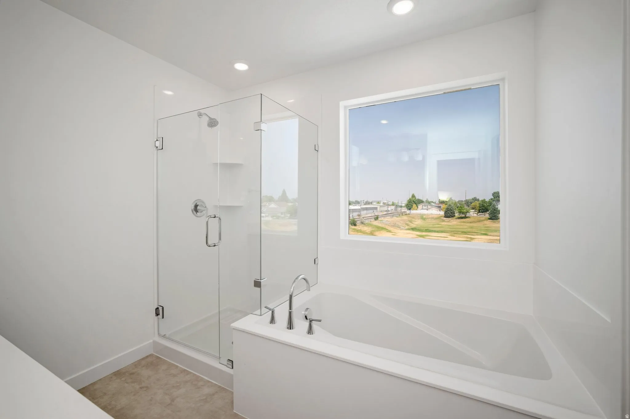 Glass-enclosed shower with chrome fixtures, built-in shelving, and a large soaking tub with a deck-mounted faucet