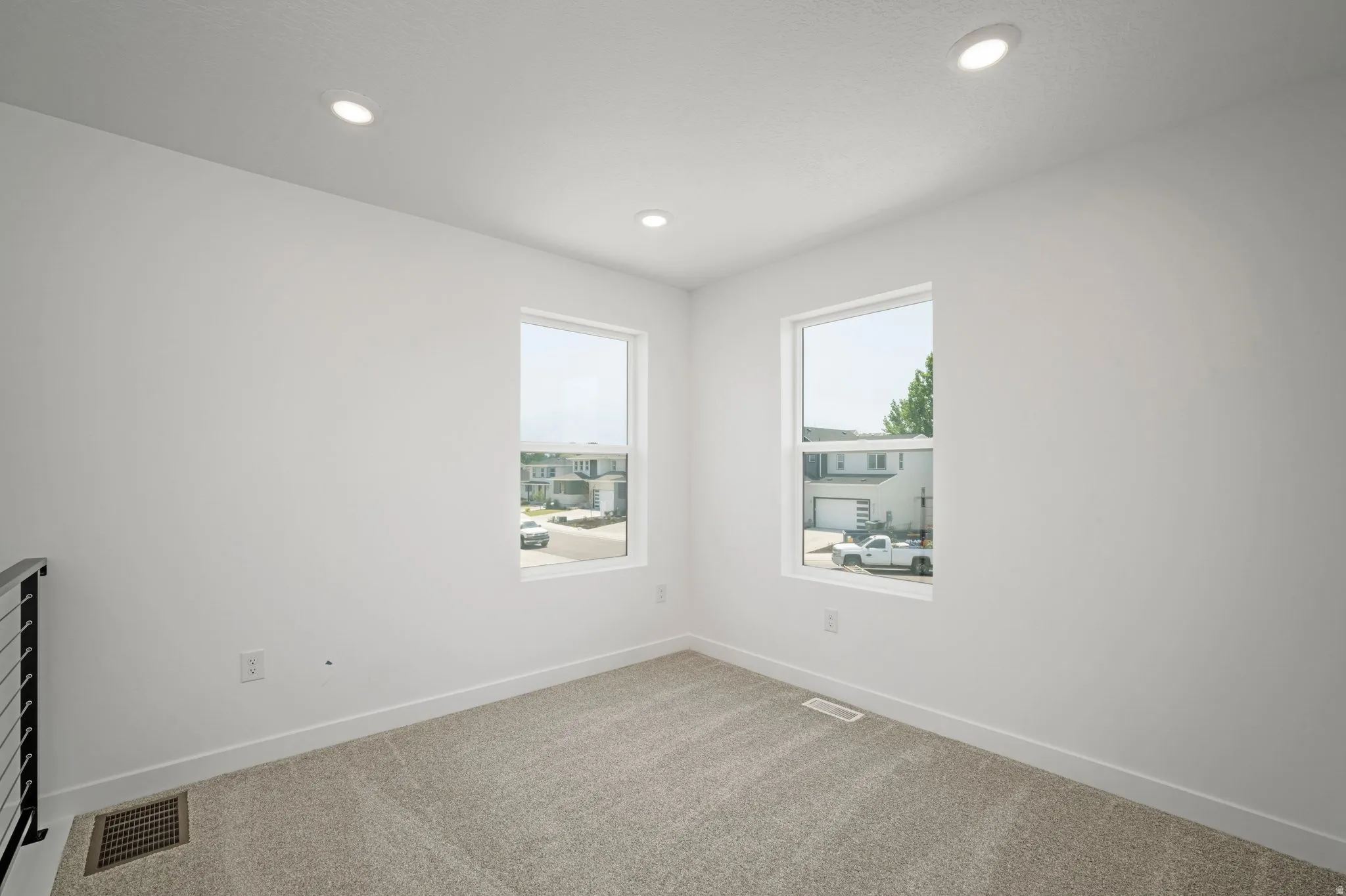 Recessed ceiling lighting, two windows, wall-to-wall carpeting, and white wall finishes
