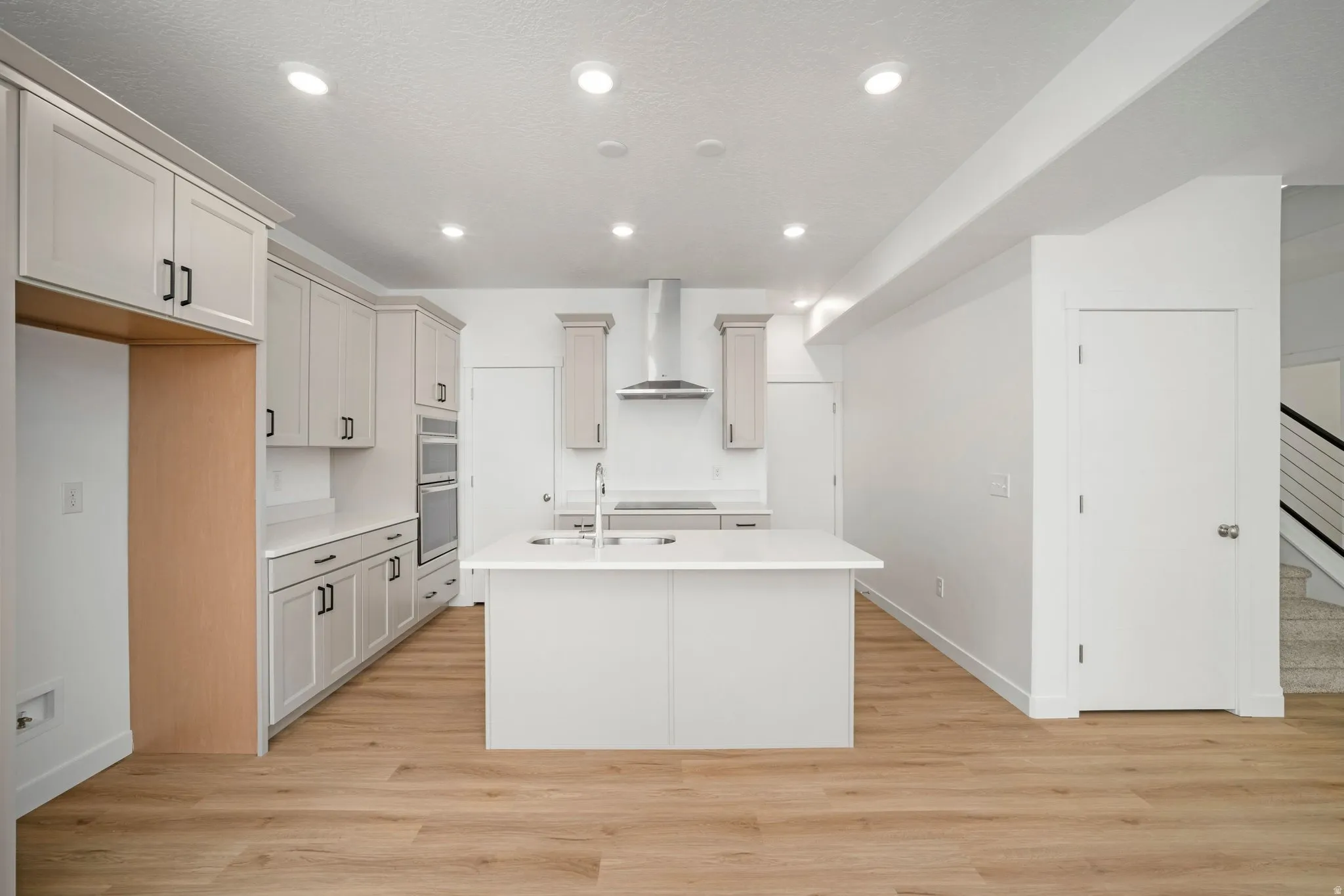 Contemporary kitchen featuring wood-finish flooring, recessed lighting, a center island, light-toned cabinetry, and stainless steel appliances