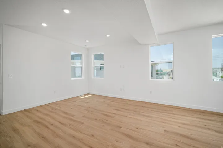 Recessed ceiling lighting, multiple windows, wood-finish flooring, white walls, and a white ceiling