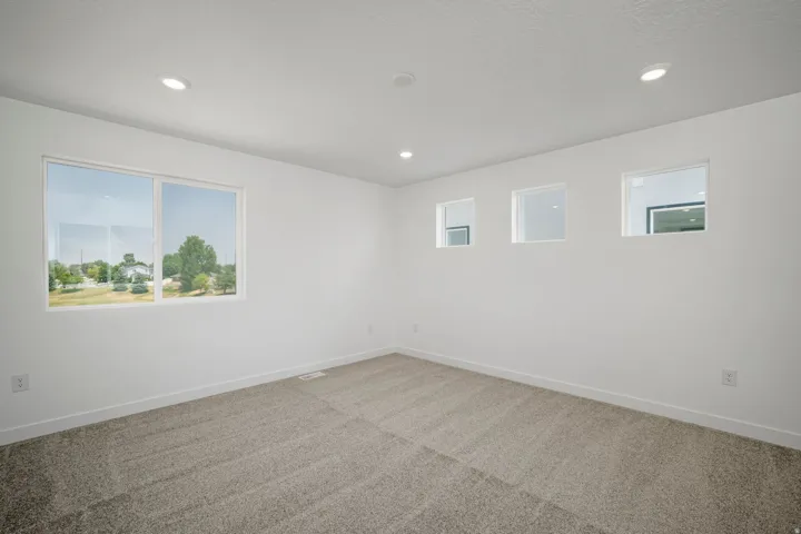 Recessed ceiling lighting, white walls, carpet flooring, a large window, and three smaller windows