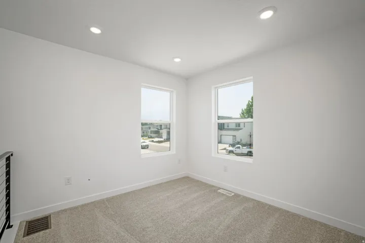 Recessed ceiling lighting, two windows, wall-to-wall carpeting, and white wall finishes