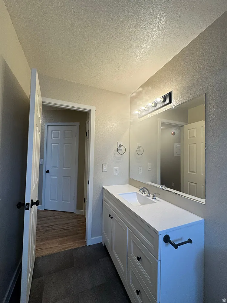 Vanity with integrated sink, white countertop, and dark hardware