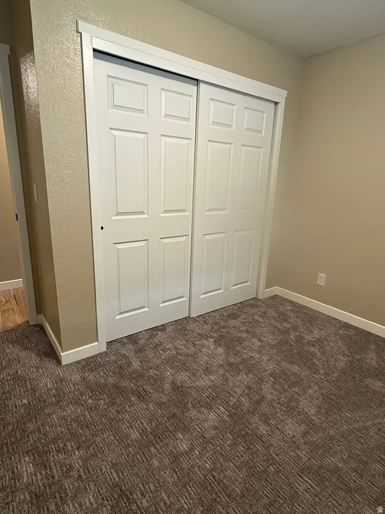Recessed closet featuring paneled bi-fold doors with white trim, set against neutral wall tones and patterned carpeting