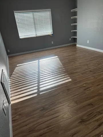 Wood-finish flooring, built-in shelving, and window with blinds