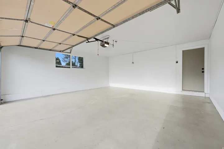 Spacious garage featuring a concrete floor, white walls, and a window for natural light