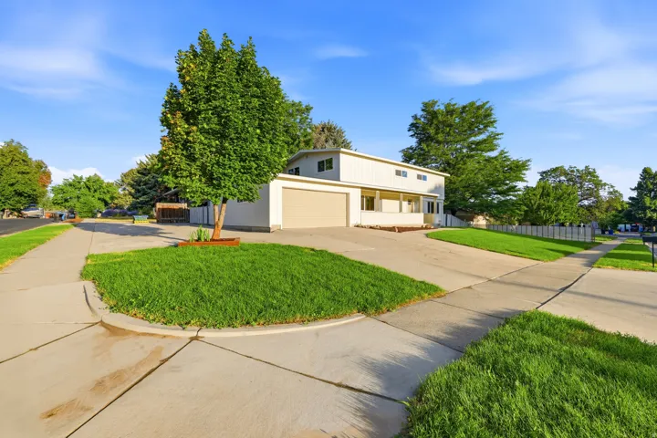 Two-story residence featuring light-colored siding, an attached garage, and a covered porch