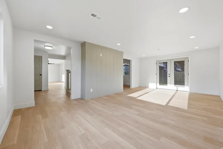 Recessed lighting, wood-finish flooring, white walls, and French doors with privacy screens