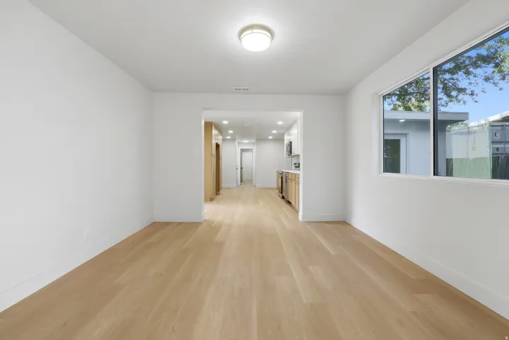 Recessed lighting, wood-finish flooring, white walls, large window, and flush mount ceiling light