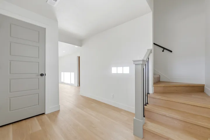 Light wood-finish flooring extending through the entry, with a painted paneled door