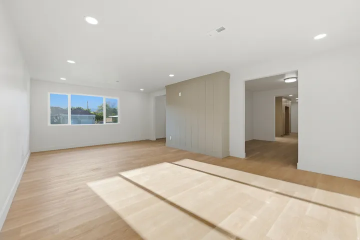 Bright room featuring light wood-finish flooring, recessed lighting, and a large multi-pane window