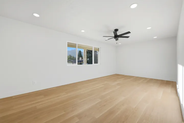 Bright room featuring recessed lighting, wood-finish flooring, a ceiling fan, and multiple windows