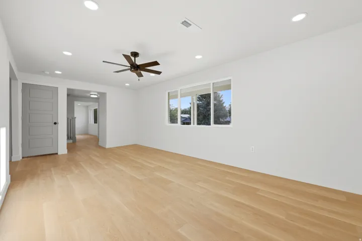 Recessed lighting, wood-finish flooring, a contemporary ceiling fan, and a multi-pane window